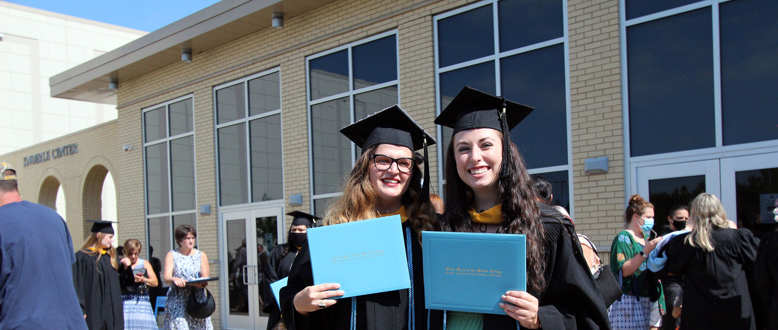 Graduates hold up their diplomas after the 2020 commencement