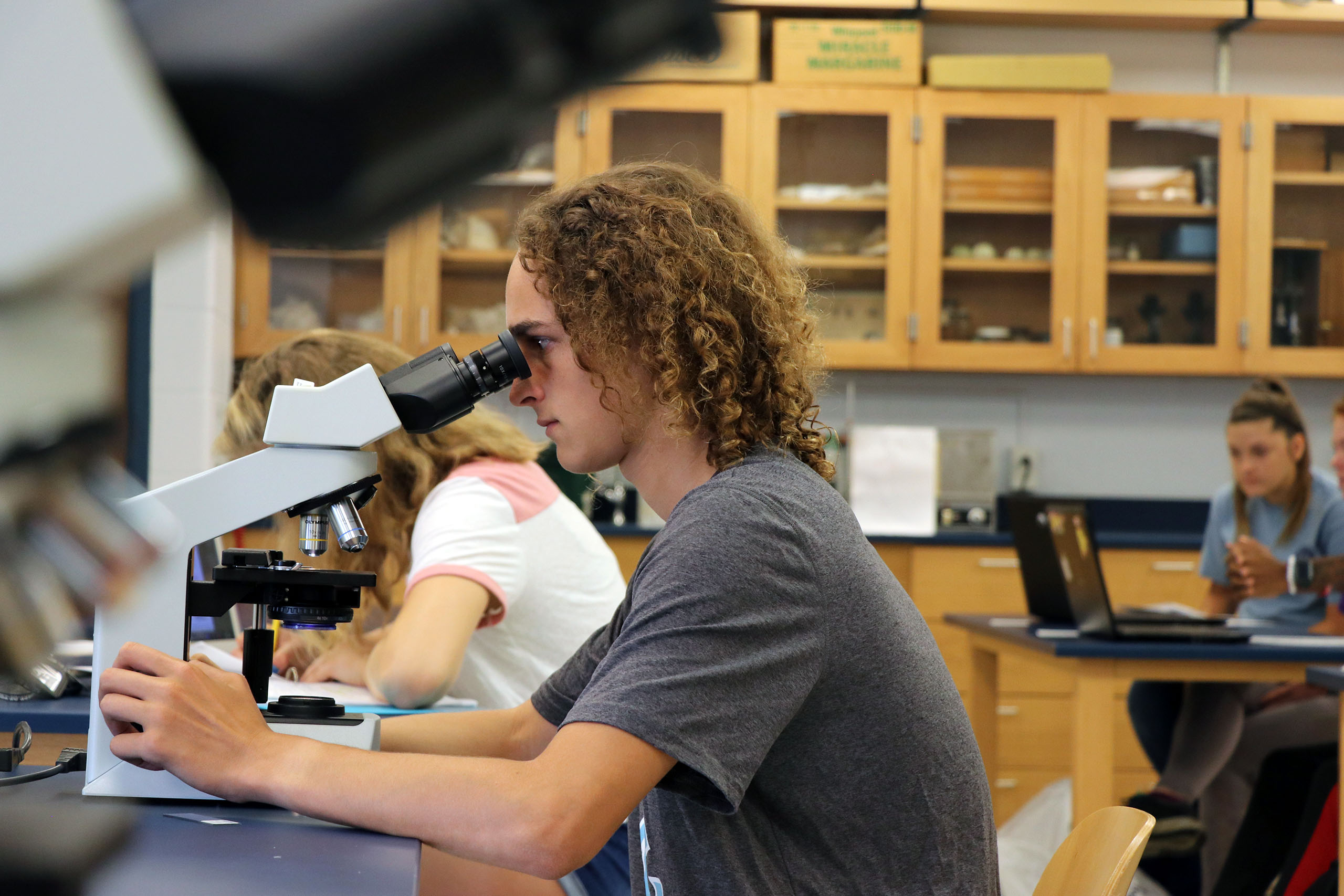 Student looking into a microscope during science class.