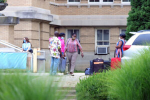 A family carrying luggage in front of Le Fer