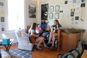 Students playing guitars together in a dorm room