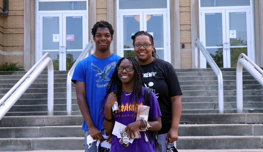 Family stands together in front of Le Fer Hall