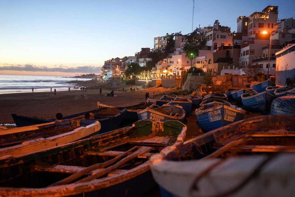 Boats sitting on the beach at sunset