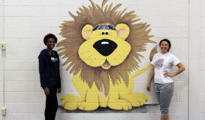 SMWC students standing in front of lion mural
