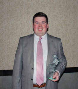 AJ Dinkel holding his top 12 under 40 award