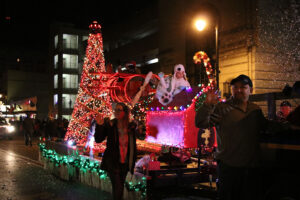 Parade float covered in lights with lifesize toy airplane on top