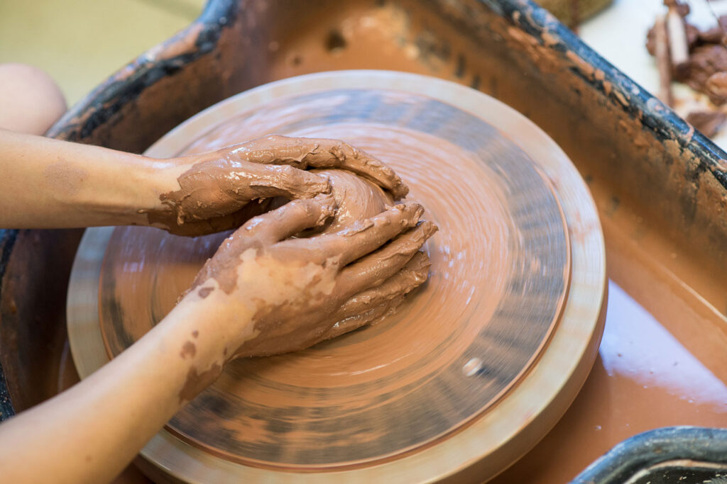 Art student molding piece of potter on wheel