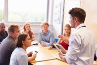Small group of high school students with a teacher talking to them.