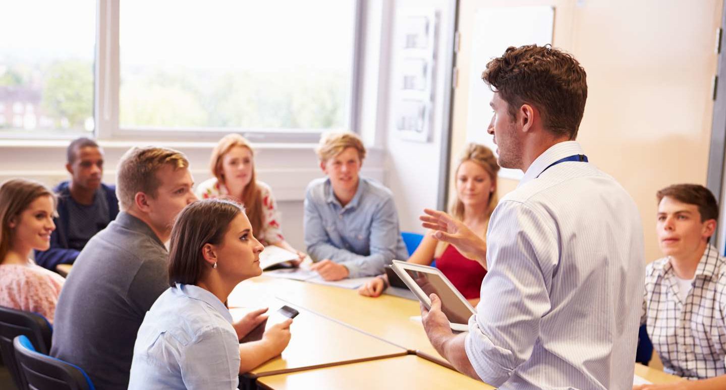 Small group of high school students with a teacher talking to them.