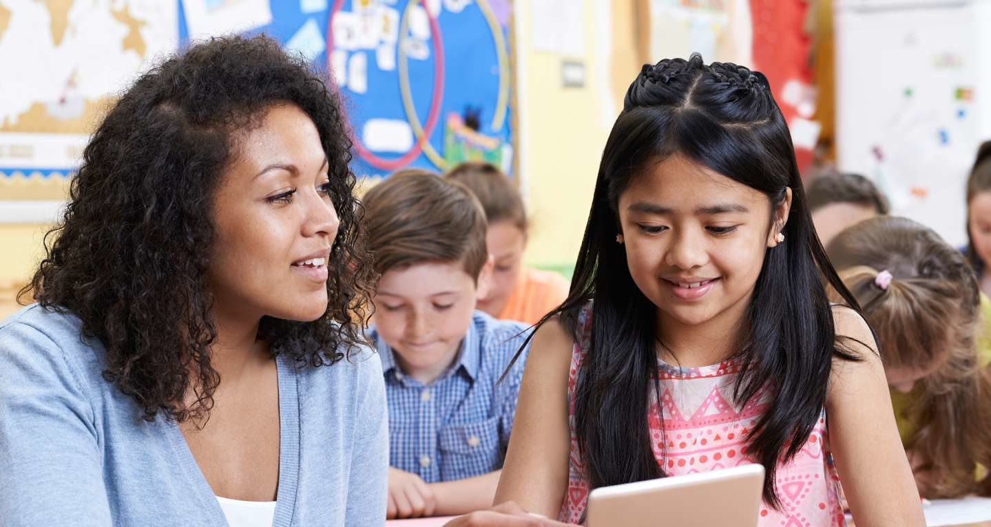 A teacher is working one-on-one with a young girl.