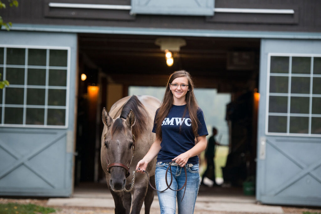 Equine student leading horse out of the stable