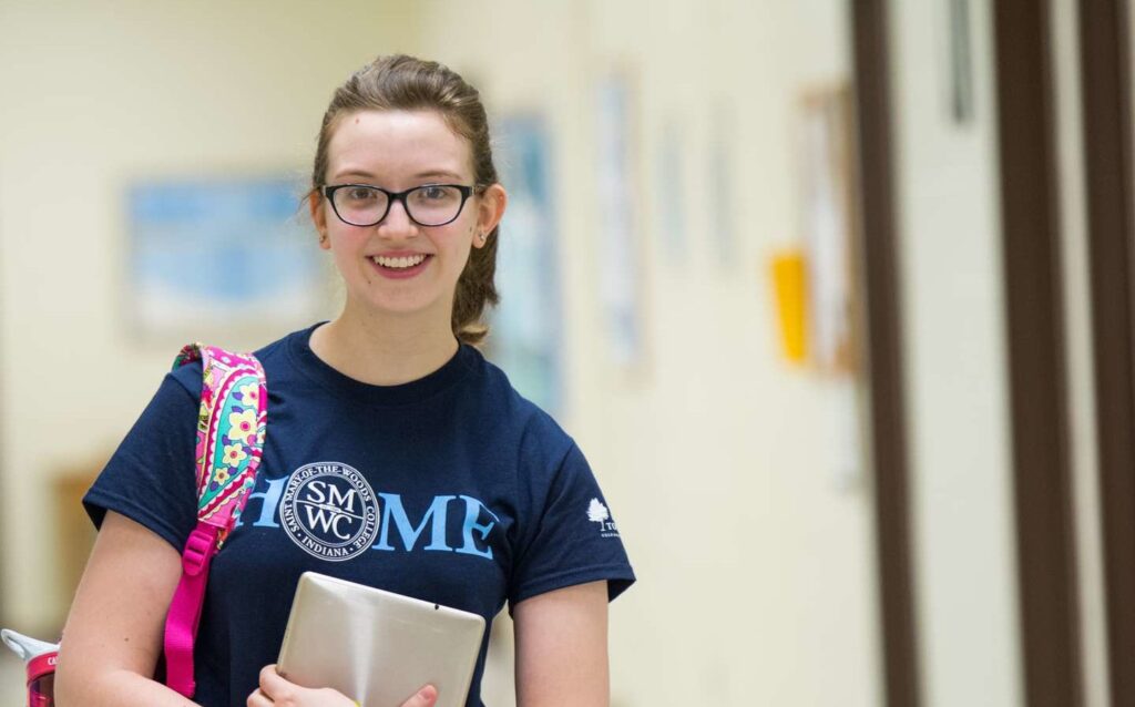 A student standing in the hall smiling.