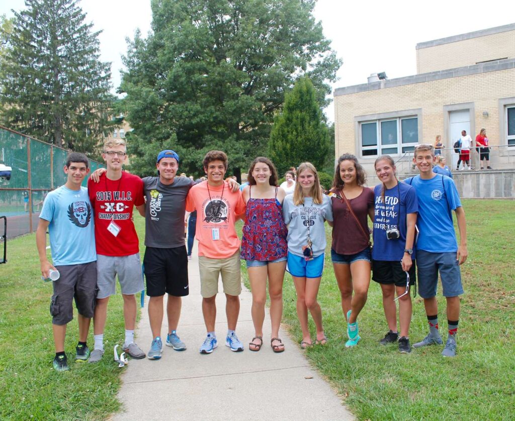Male and female students with linked arms smiling.