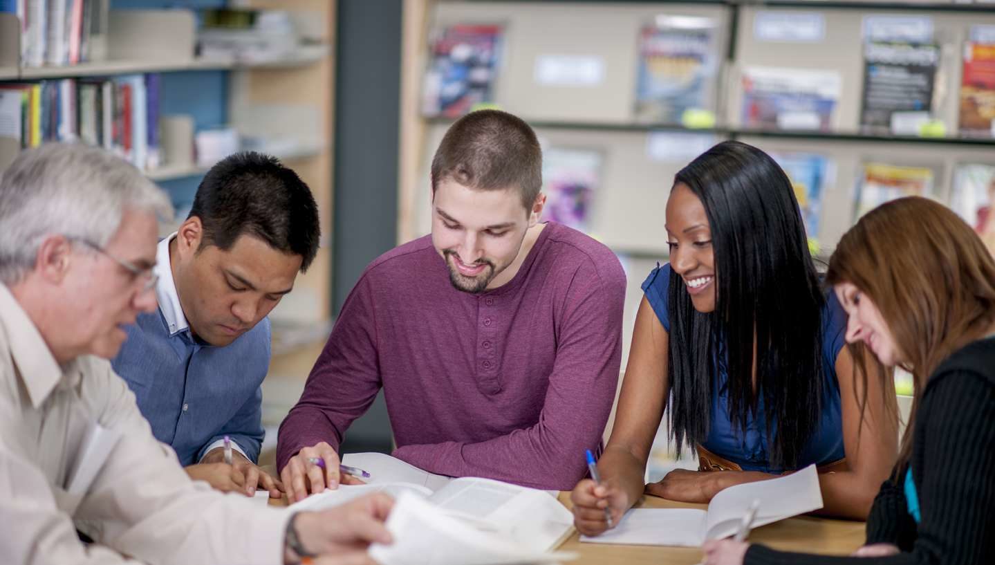 Adult students at a table studying together.