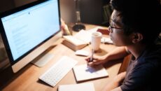 A male student studying in the evening light at his desk.