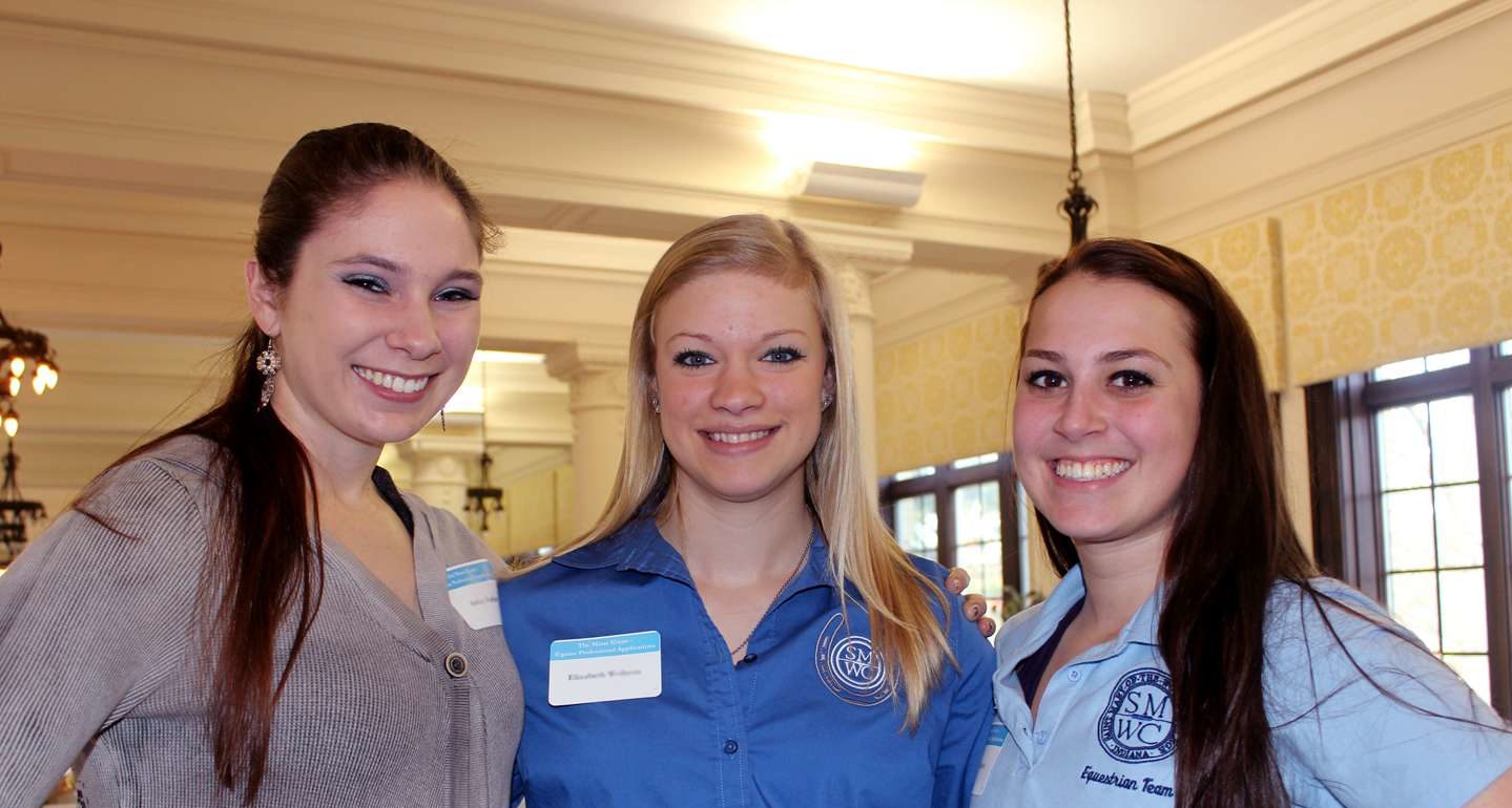 An equine alum standing with two students smiling.