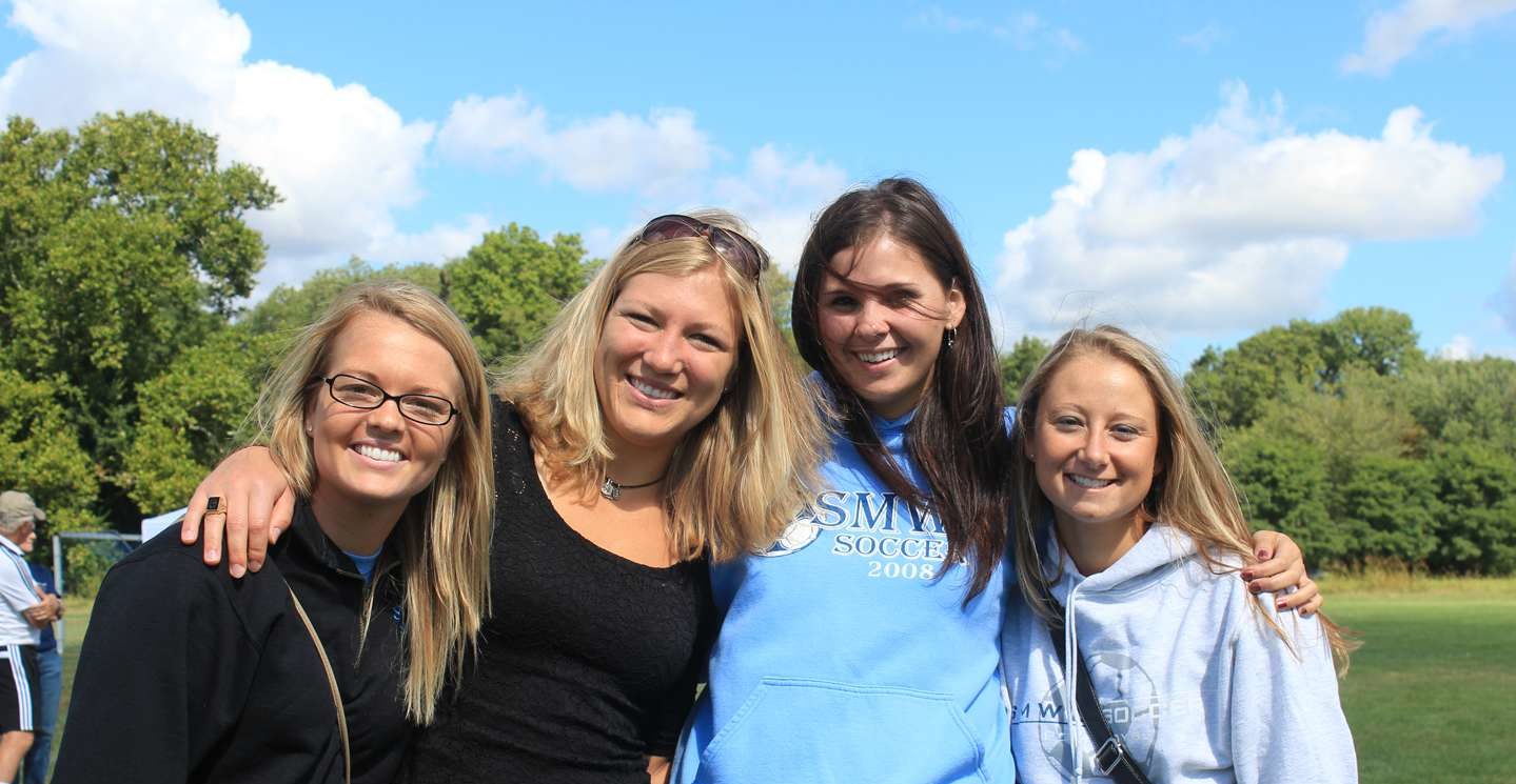 Four women alums smiling at Homecoming.