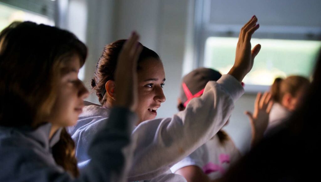 Students hold up their hands in a classroom.