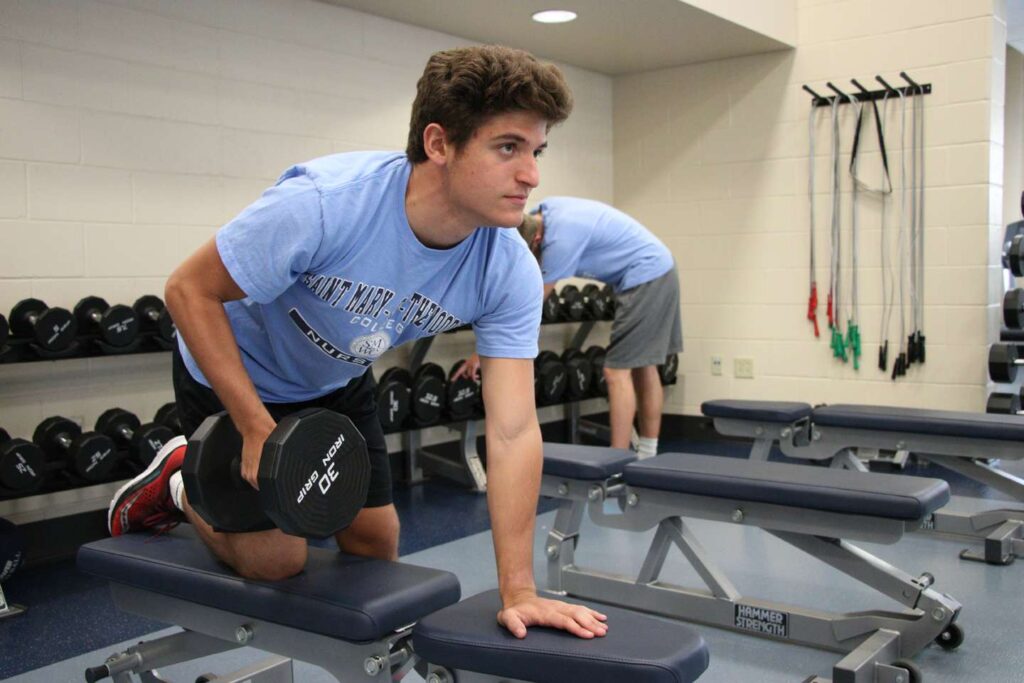 A male student lifts weights in the fitness center.