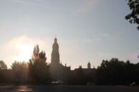 The sun rising up over the trees with the silhouette of the Chuch of the Immaculate Conception.